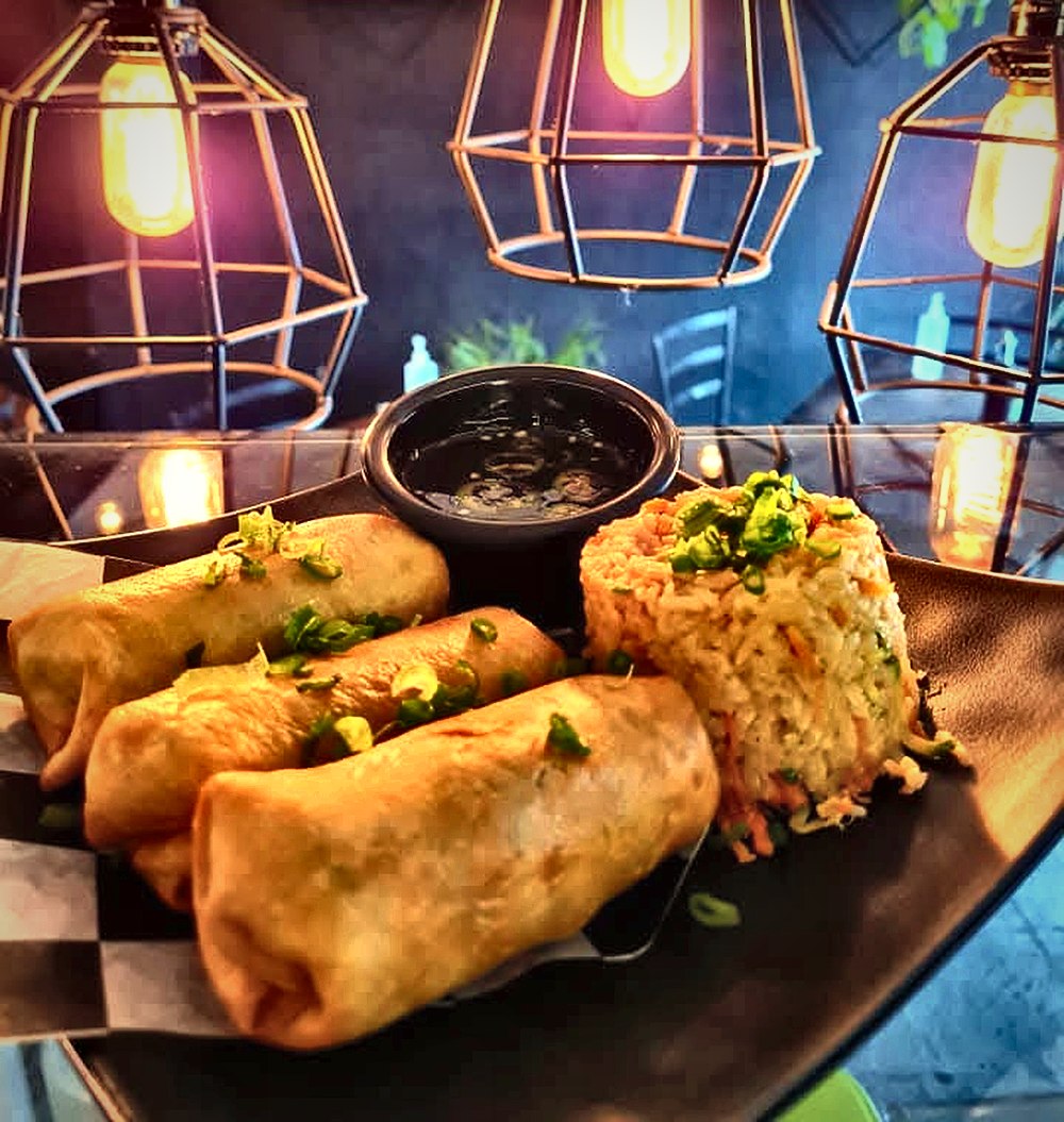 Rollos primavera dorados con una porción de yakimeshi y salsa